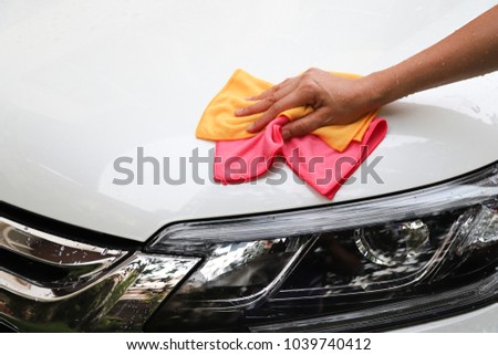 Closeup of white car cleaning  with yellow and pink microfiber cloths by woman's hand. Royalty-Free Stock Photo #1039740412