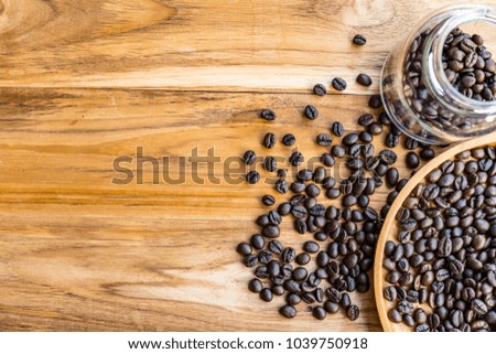 Roasted coffee beans in a circular wooden tray placed on a wooden floor. Closeup photo shows the details of the coffee beans. Photo taken with natural light