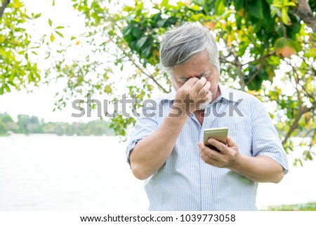 Senior man trying to use a mobile device. Very confuse old chinese man trying very hard to use his smart phone. Not happy as he struggle. Royalty-Free Stock Photo #1039773058