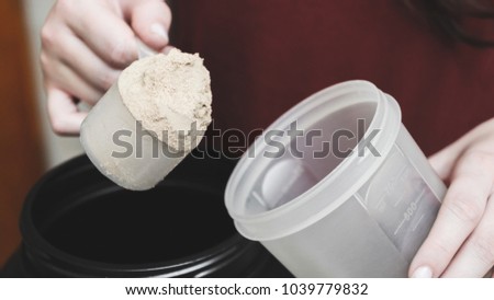 Going to pour casein protein powder into the cup. Fitness supplement food. Royalty-Free Stock Photo #1039779832