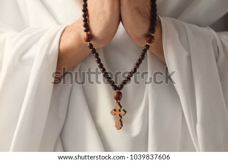 Praying monk with rosary beads, closeup