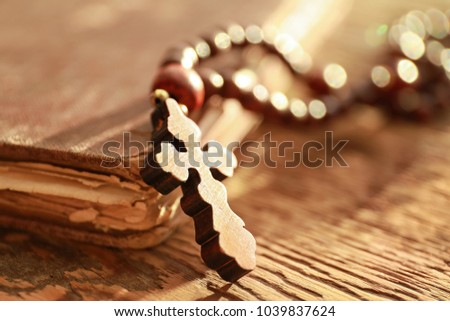 Rosary beads with cross and book on wooden background, closeup