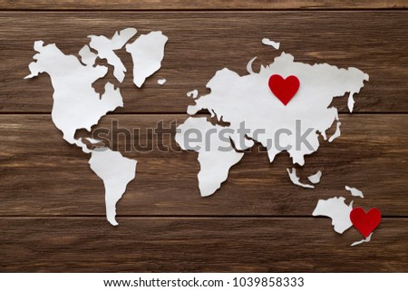 Red felt heart and world map cutted from white paper on the wooden background. Long-distance relationships concept - Russia and New Zealand. Flat lay, top view, copy space, mock up