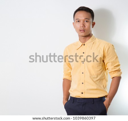 Attractive  young business man wearing orange  shirt and blue pants  while posing in a studio setting on a white background and looking at the camera