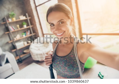 Close up portrait of excited active attractive cheerful beautiful strong skinny with beaming smile wearing sportive top with jump-rope on shoulders taking selfie for social-networks