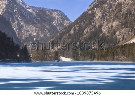 Partly frozen lake in winter with mountains in the background