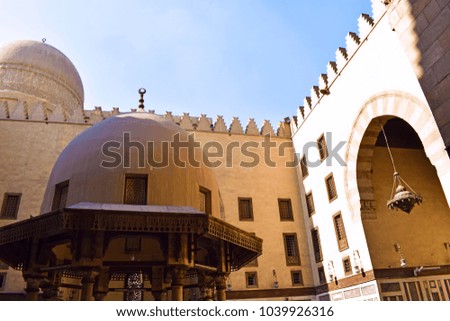 Inside the courtyard of an ancient mosque in the ancient region of Egypt showing the beauty of the Islamic architectural design of windows and lamps and giant doors