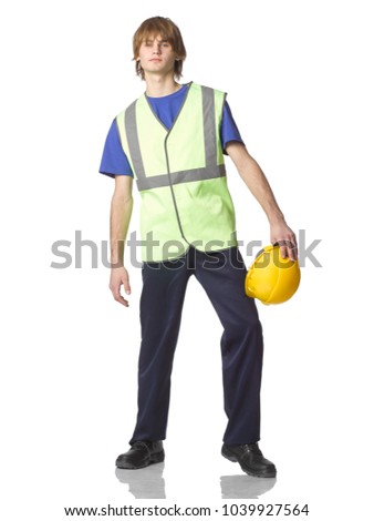 Young guy builder or trainee in work clothes with protective helmet in hands isolated on white background.