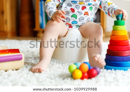 Closeup of cute little 12 months old toddler baby girl child sitting on potty. Royalty-Free Stock Photo #1039929988