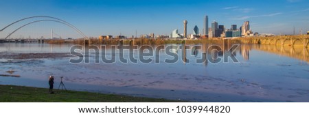 This is the picture of a photographer taking picture of Dallas skyline during sunet with reflection on Trinity River, Dallas, Texas.