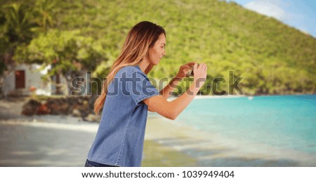 Millennial girl taking photo of ocean waves with cellphone and sharing them