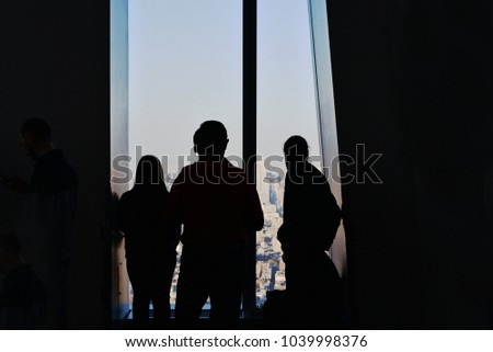 Silhouetted strangers enjoying New York view.