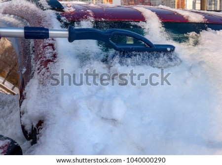 A machine is cleaned by a brush from snow on parking.