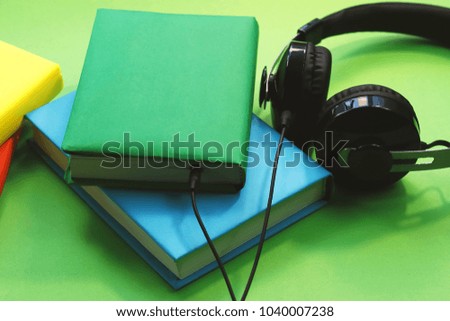headphones and books in colored wrappers. on a green background. concept of audiobook.