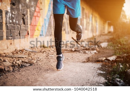 Young handsome sportive man running outside at sunset. Successful young active man. Running legs.