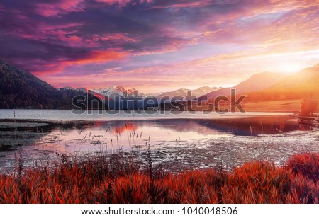 Magical Sunset Over the Mountains lake. Colorful sky under sunlit reflected in water. Awesome alpine highlands in sunny day. Picture of wild area. Wonderful Natural Background, view with Dramatic sky 
