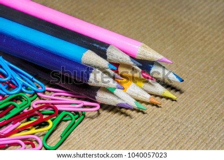 a lot of colorful penciles set in a row with  paper clips