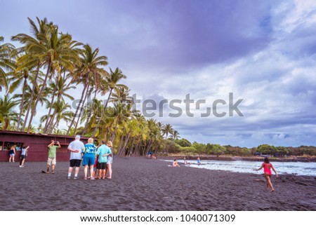 Group of people taking pictures on a black sand beach of Big Island Hawaii