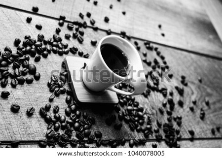 Unique design white espresso cup with black coffee beans. black and white photography on wood or wooden surface or table