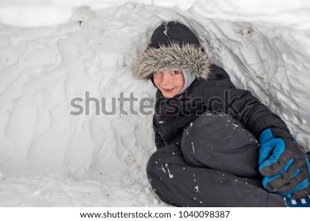 A five year old boy inside his igloo, United Kingdom