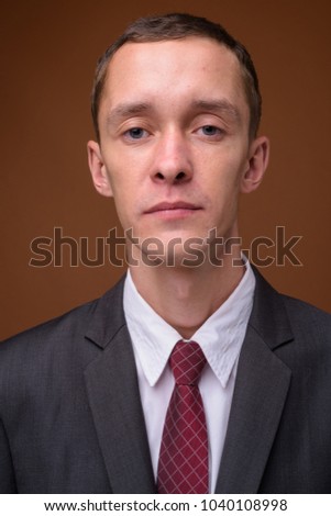 Studio shot of young businessman wearing suit against brown background