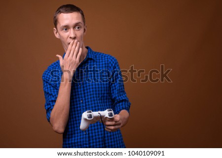 Studio shot of young man playing games against brown background