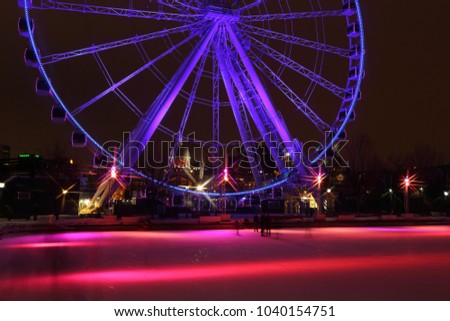 Great wheel of Montreal panoramic colorful silhouette by night. Luminous colorful ferris wheel in the Old Port. Public ice rink in downtown.