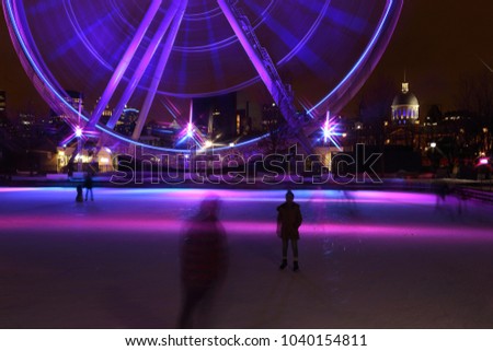Great wheel of Montreal panoramic colorful silhouette by night. Luminous colorful ferris wheel in the Old Port. Public ice rink in downtown.