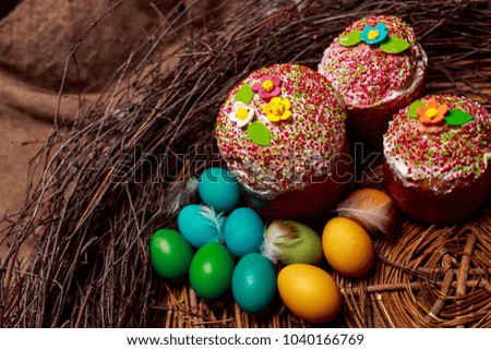 Easter cakes and colored eggs in a wicker nest