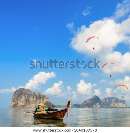 Limestone mountain seascape  and wooden long-tail boat with Paragliding over Pak Meng Beach in Trang province, Thailand