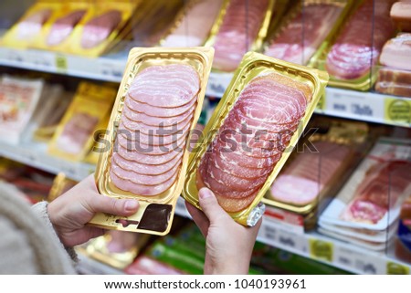 Woman chooses a slice of ham and meat  in vacuum package at the grocery store Royalty-Free Stock Photo #1040193961