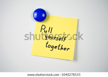 yellow sticker inscription Pull yourself together attached  blue magnet  white fridge. close-up
