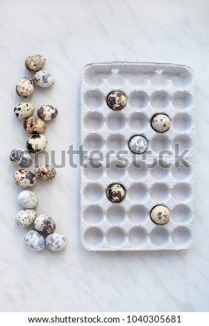 Spotted quail eggs on marble surface and cardboard box with eggs