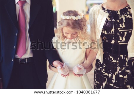Little Girl in her First Communion Day with Her Father and mother. Royalty-Free Stock Photo #1040381677