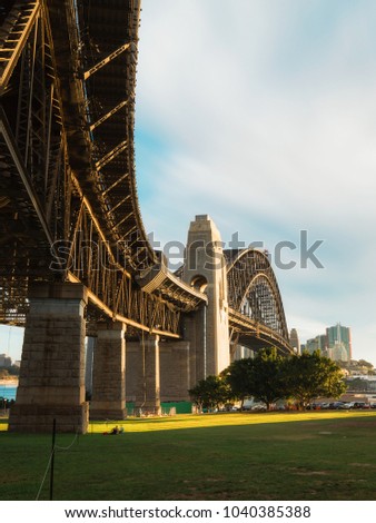Long exposure of Sydney Harbour Bridge with sunny sky on golden hour. Taken from below on the northern side.