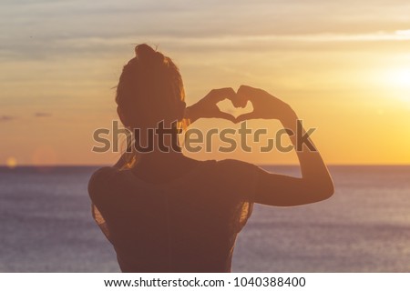 Girl holding a heart - shape symbol with her hands / fingers. Royalty-Free Stock Photo #1040388400