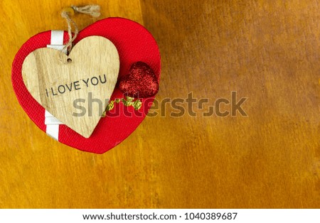 base invitation wooden heart carved with the phrase I love you and a festive box with copy space on rustic background, design festive saint patric