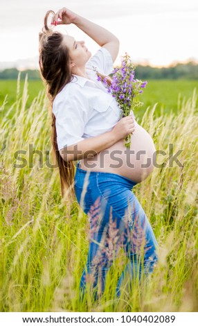 beautiful pregnant woman in the field at sunset