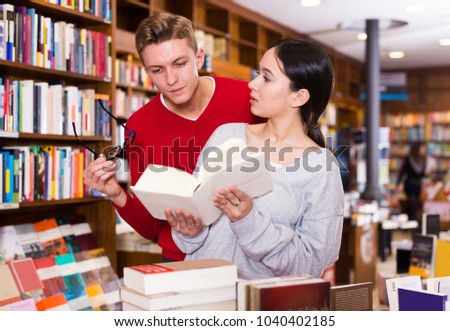 young girl and a man reading and discussing a book in a bookstore 