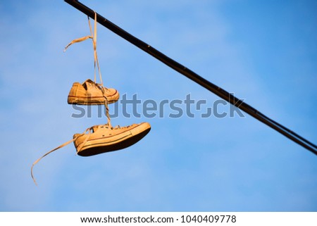 Old Shoes hanging on electrical wire against a sky
