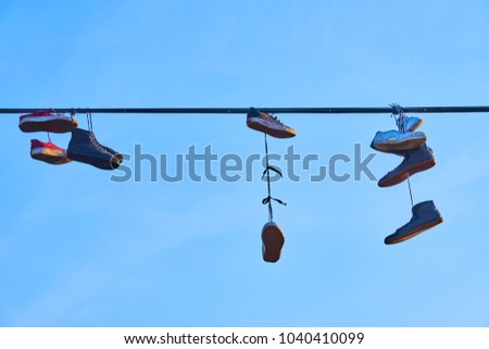 Old Shoes hanging on electrical wire against a sky.
