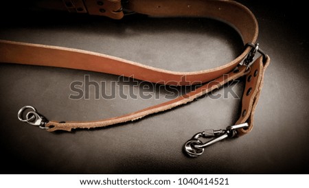 A beautiful brown hand made leather camera sling strap on a black background. Photographer equipment, stylish, vintage, retro feel.