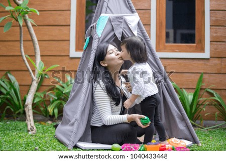 Mom and her daughter are playing and having fun together in a tent. kissing