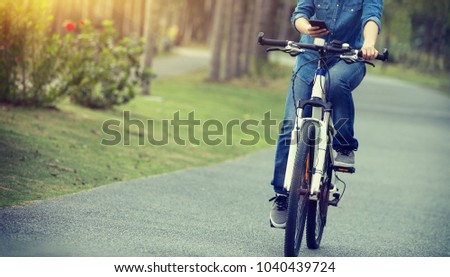 cyclist use cellphone while riding bike in tropical park