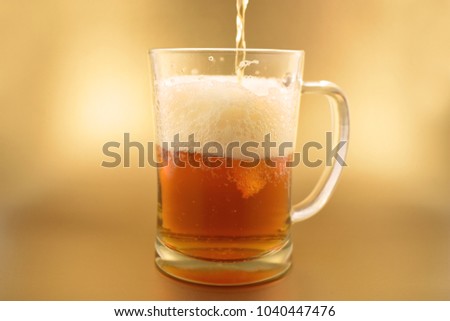 Glass with beer stock images. Glass with beer on a golden background. Beer on a golden background with copy space for text. Festive golden background