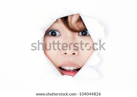 Young woman peeping through hole on paper