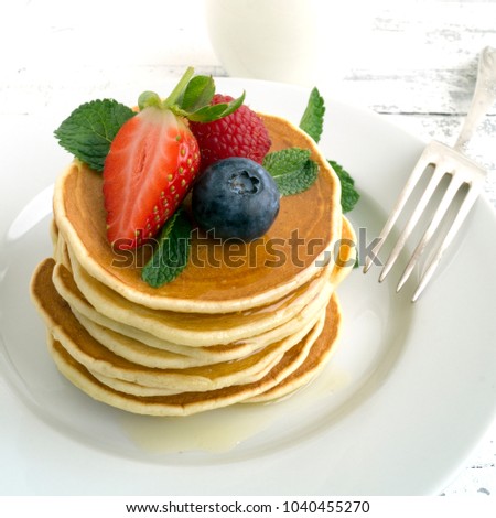 American pancakes with berries on a light background.
