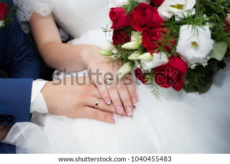 Wedding rings on the fingers of the bride and groom on the background of a wedding bouquet. Closeup.