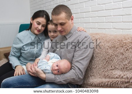 family photo, father mother and son are admiring the baby