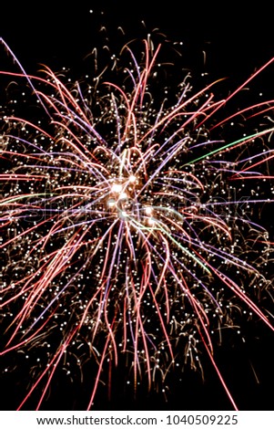 Explosion of firework against the background of the night sky. Multi-colored lines and sparks are visible